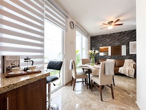 A modern kitchen with a dining area, large windows, a ceiling fan, and a view of the outdoors. - Las Canoas Zona Romantica By Monyxbnb (Puerto Vallarta)