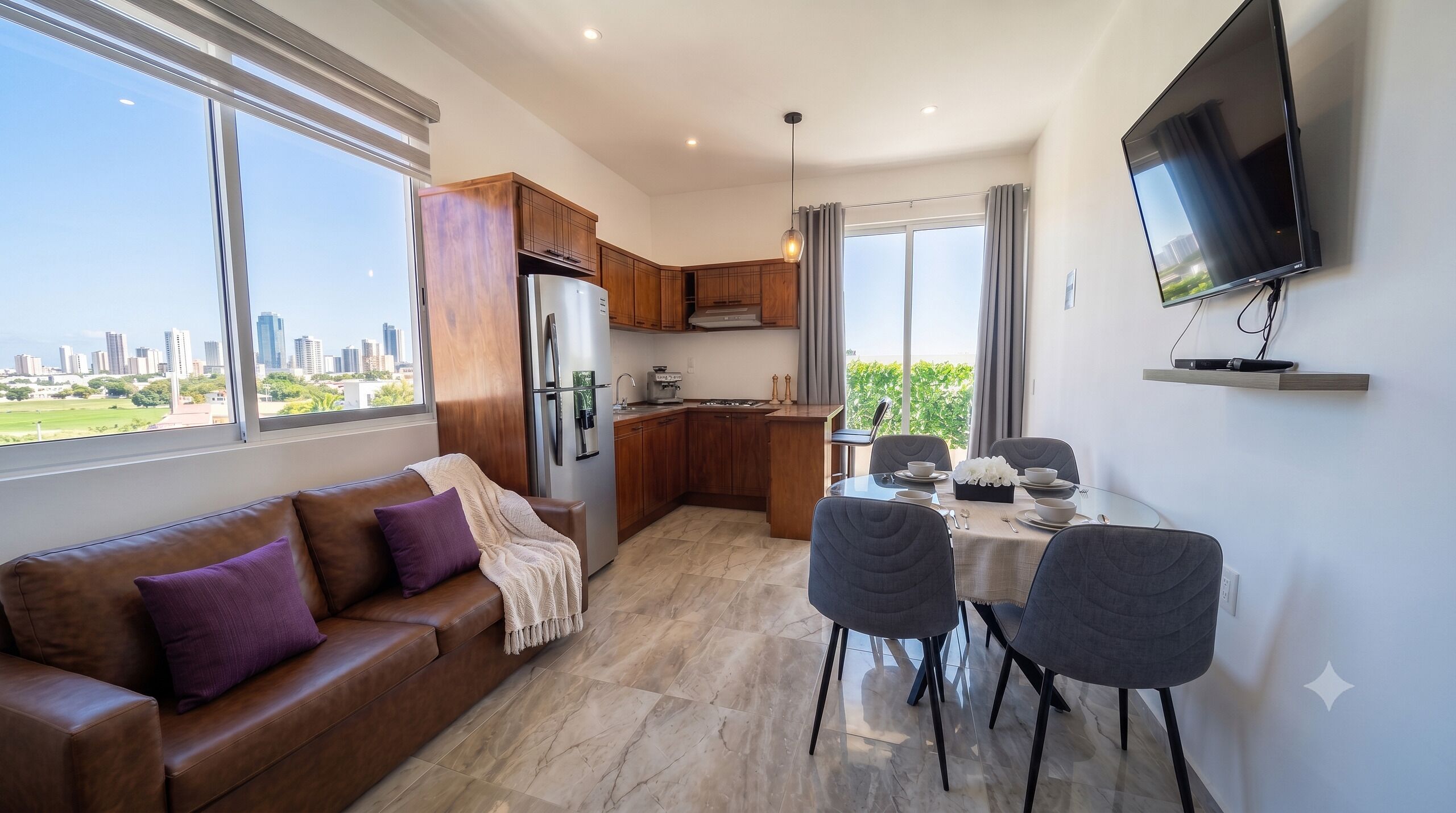 A modern apartment with a living room, kitchen, dining area, and a TV mounted on the wall.