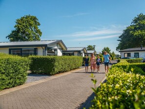 A pathway lined with modern houses, a clear sky, and greenery. - Holiday Home in Noordwijk With Terrace (Noordwijk)