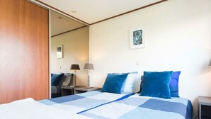 Ett hotellrum med en säng, två sängbord, ett litet bord, en spegel och en tavla som hänger på väggen.