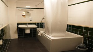 A bathroom with a bathtub, a sink, and a toilet. - Deluxe Double Room (Derby)
