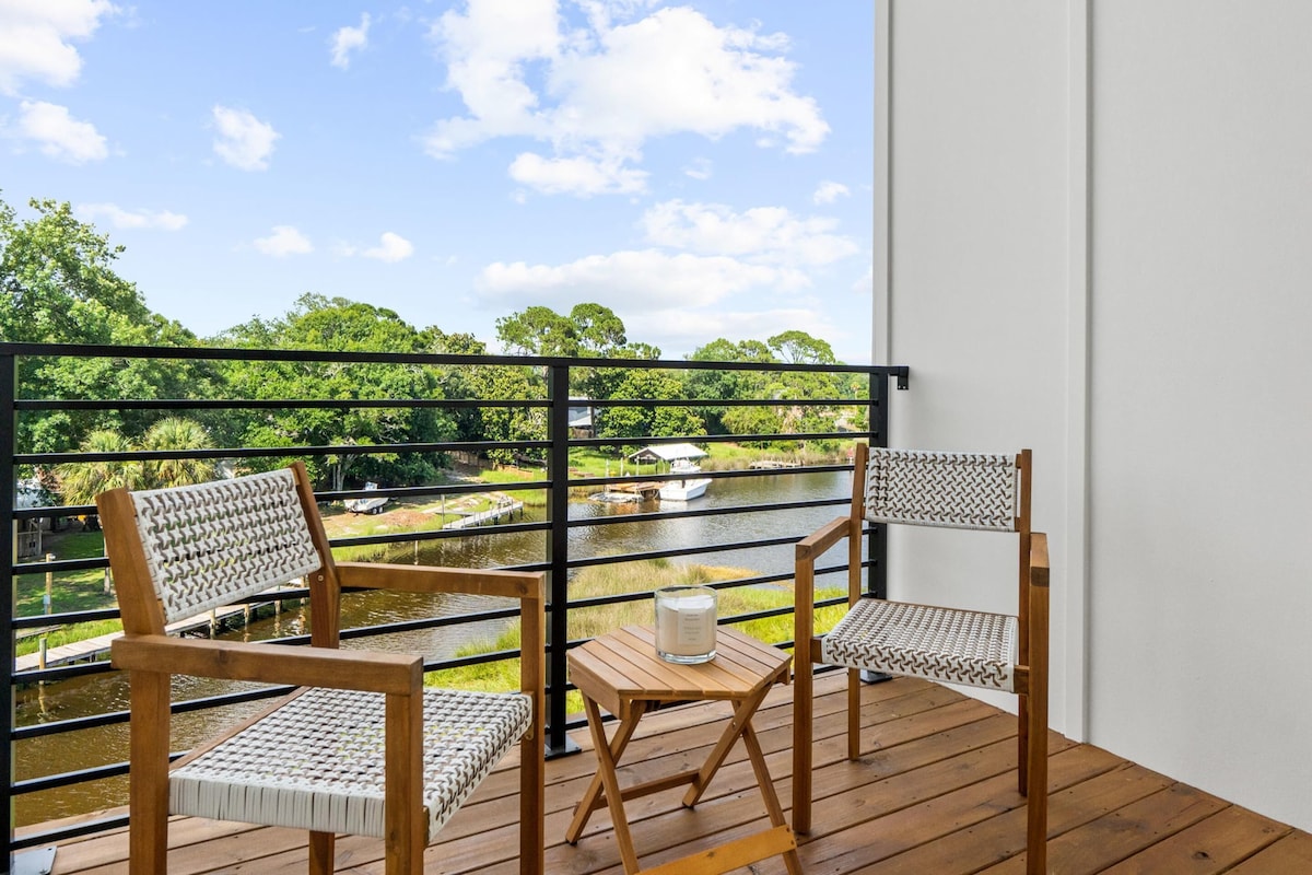 A balcony with two wicker chairs, a small wooden table, and a candle.
