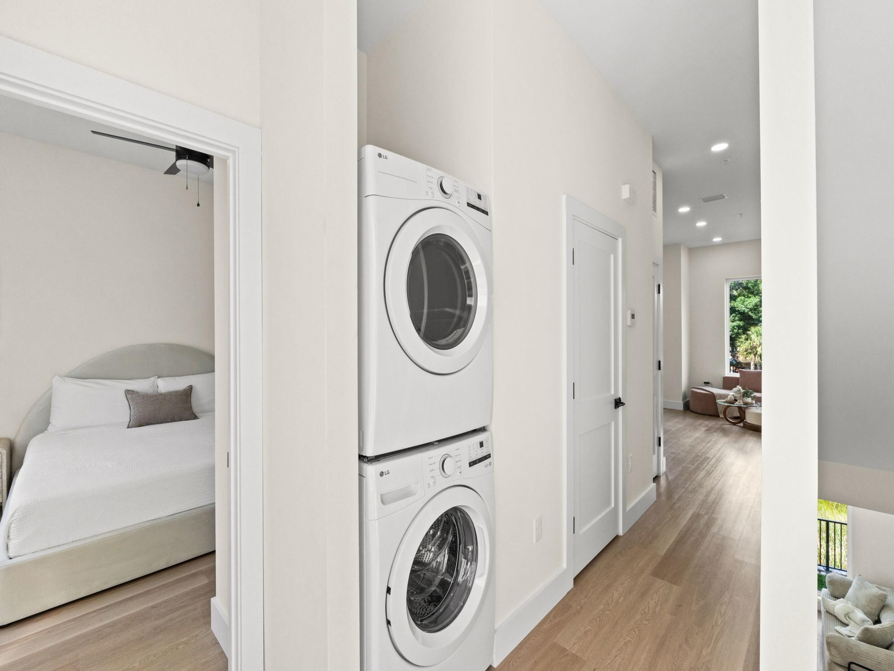 Een moderne hotelkamer met een bed, een wasmachine en een deur naar een balkon.