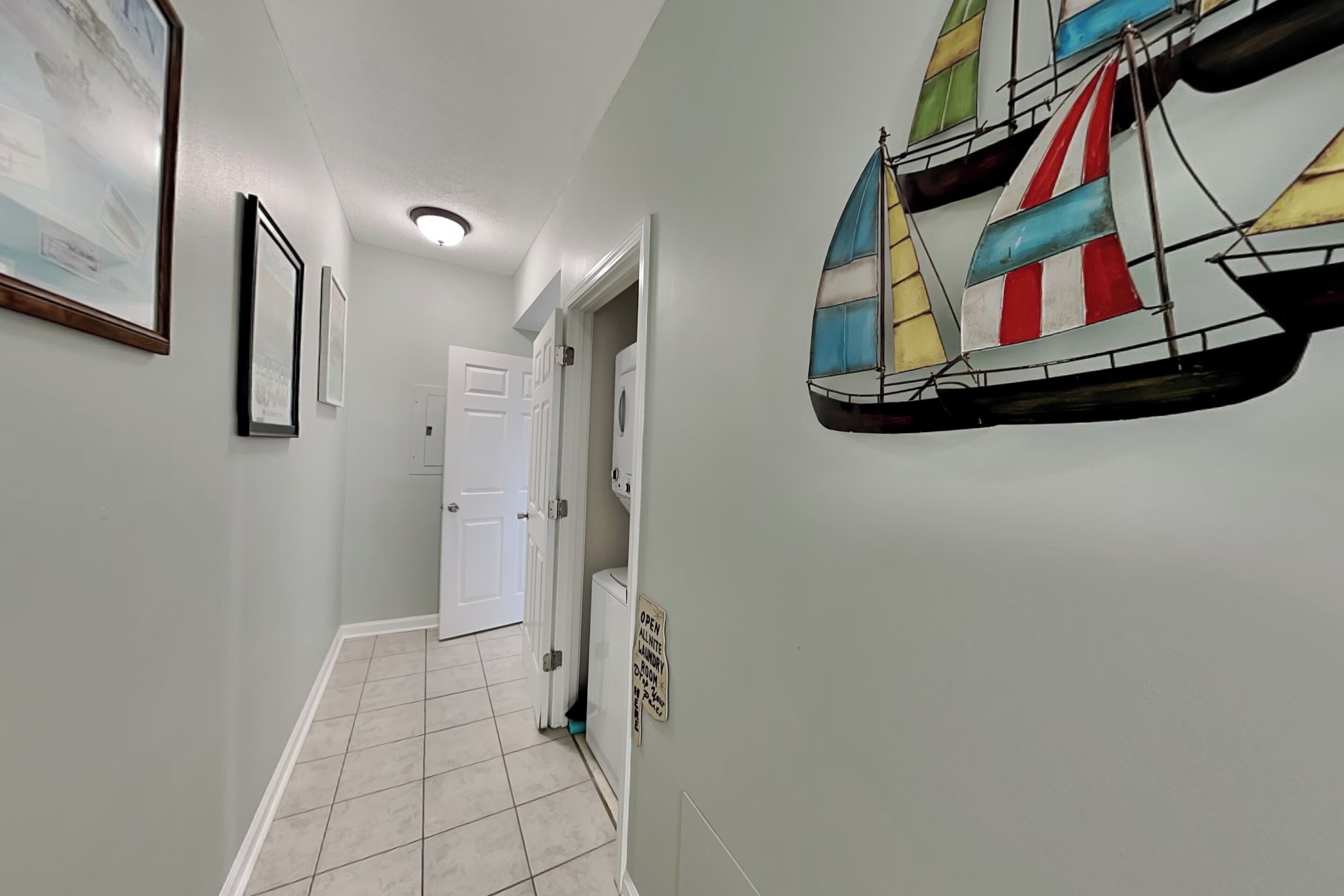 Un couloir orné de tableaux encadrés, décoré d’une maquette de voilier coloré, et sur lequel est apposée une enseigne indiquant la présence d’un service de blanchisserie.