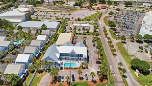 An aerial view of a commercial area with multiple buildings, roads, and parking lots. - Poinciana Place #222 - Mystic Miramar (Miramar Beach)