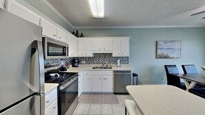 A modern kitchen with white cabinets, a stainless steel refrigerator, a microwave, and a dishwasher. - Poinciana Place #222 - Mystic Miramar (Miramar Beach)