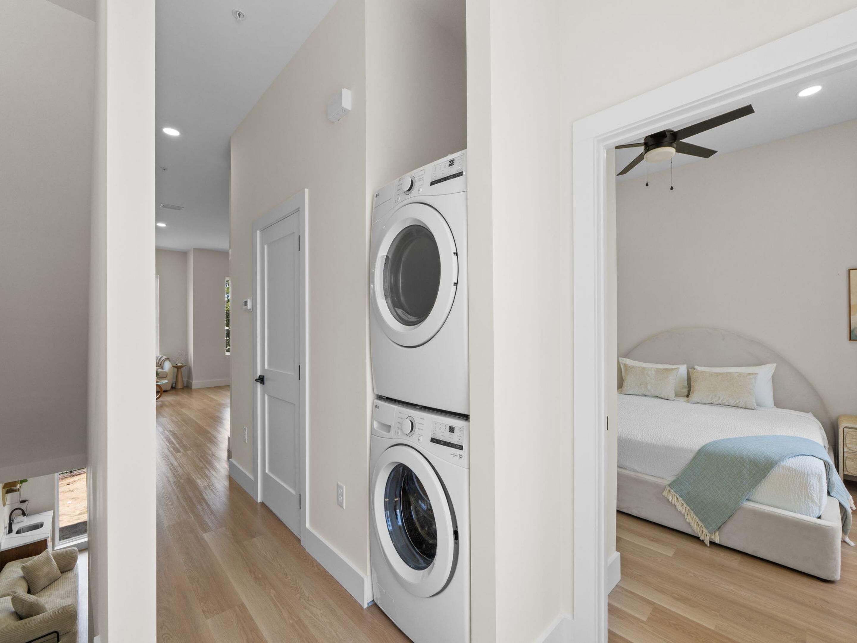 A modern bedroom with a bed, a ceiling fan, and a washing machine in the corner.