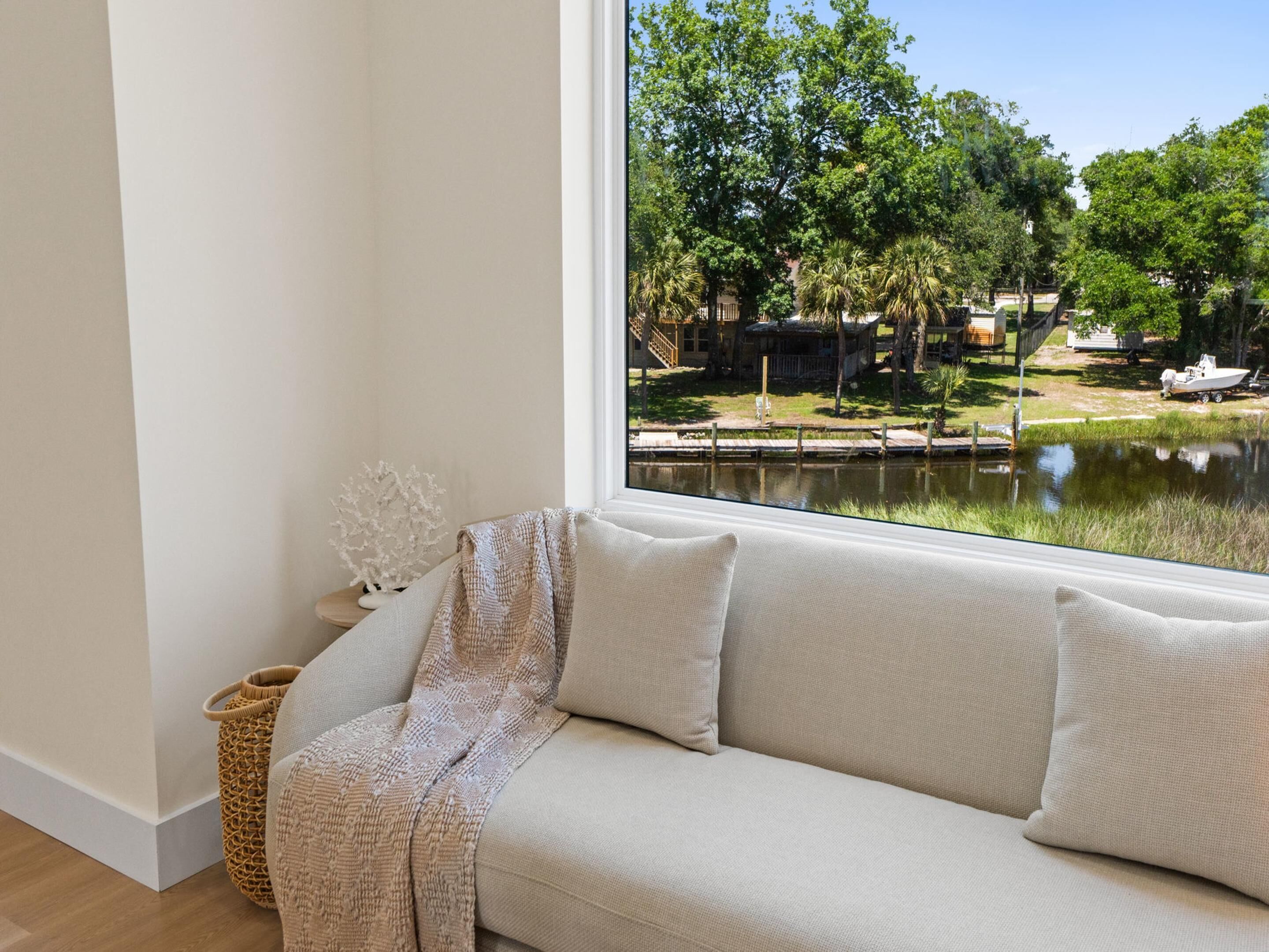 A room with a large window overlooking a water body and greenery.