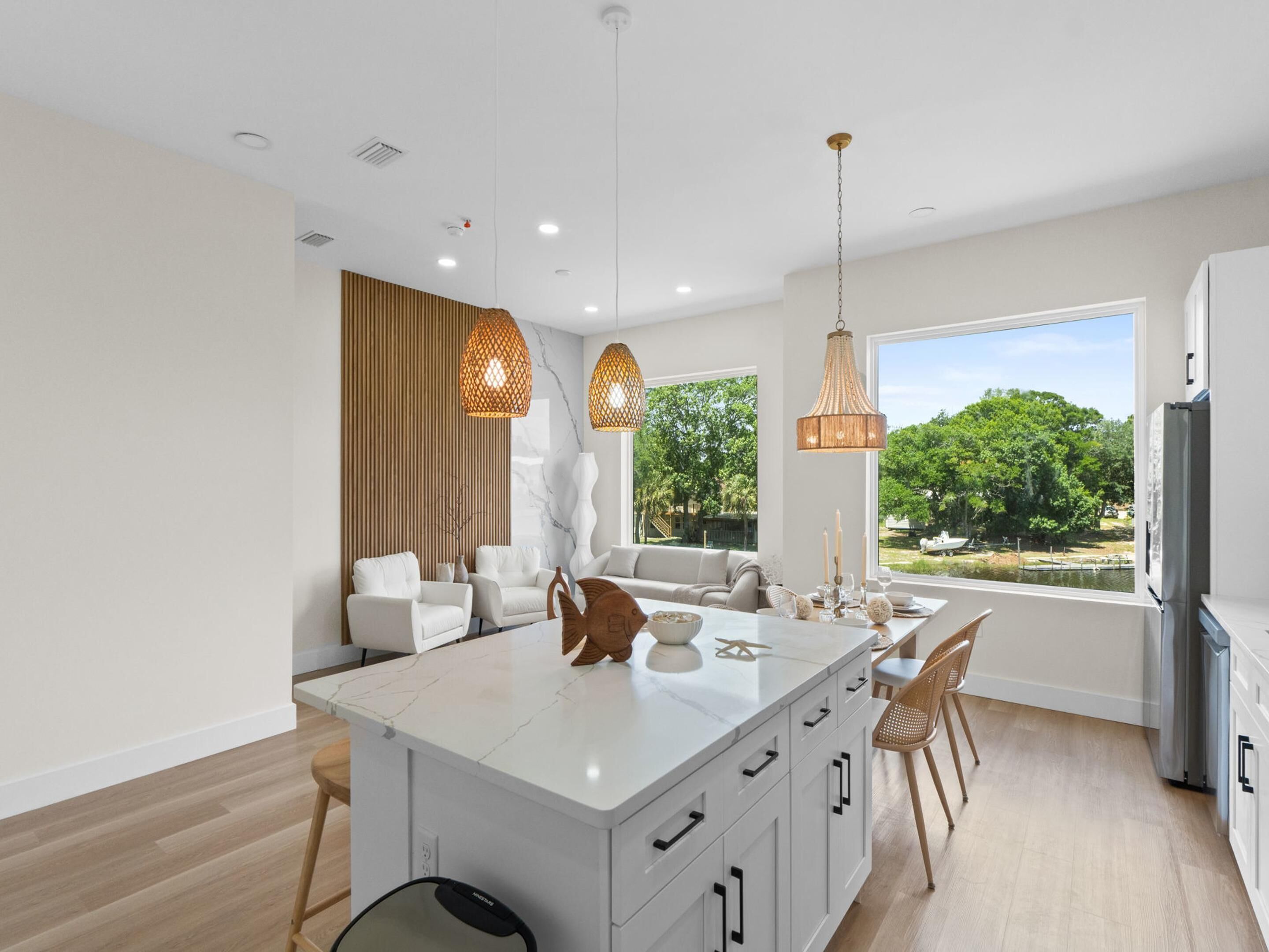 Cocina moderna con isla central, iluminación colgante y vistas a zonas verdes.