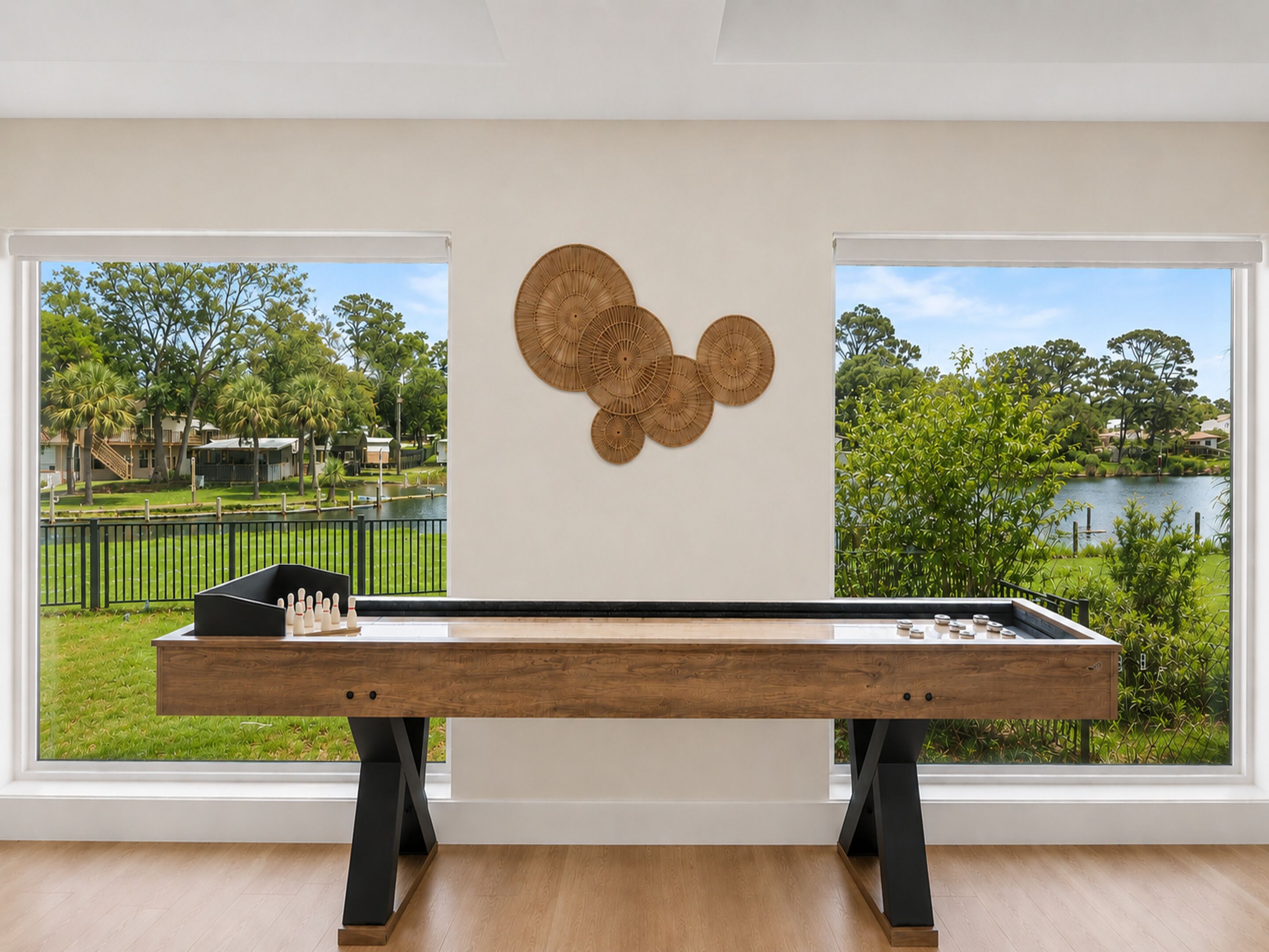A room with a wooden table, a view of a park and lake, and a wall with woven wall art.