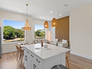 Una cocina moderna con una isla de mármol, iluminación colgante y vistas a un lago.
