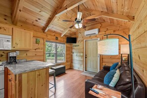 Interior de uma cabana de madeira com cozinha, sala de jantar e sala de estar.