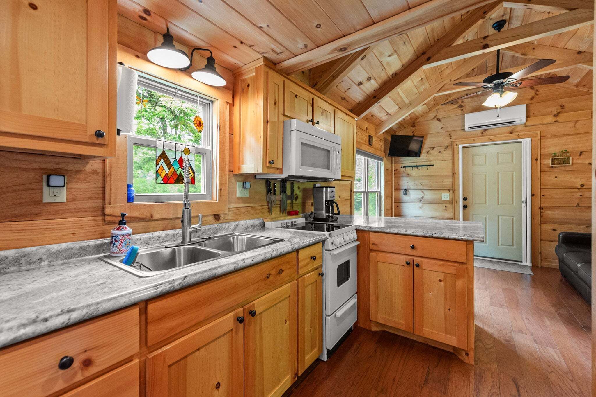 Une cuisine de style rustique, avec des éléments en bois, un plan de travail en granit, un évier en acier inoxydable, une cuisinière blanche et des armoires en bois.