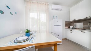 Una cucina moderna con mobili bianchi, forno integrato e zona pranzo con tavolo apparecchiato per due.