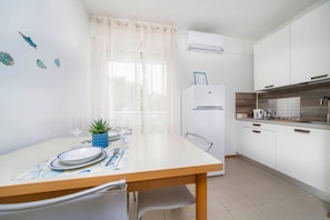 A modern kitchen with white cabinets, a built-in oven, and a dining area with a table set for two. - A comfortable 31 sqm studio apartment, perfect for two people, located on the third floor (Scala A) of a building with an elevator (NOT accessible to people with disabilities) directly facing the seafront.The property is located in Lignano Sabbiadoro in  (Lignano Sabbiadoro)