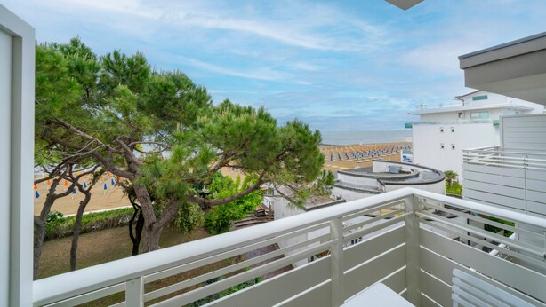 Un balcone con vista sulla spiaggia, alberi e un edificio.