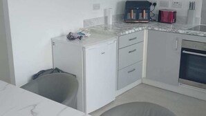 A modern kitchen with white cabinets, a marble countertop, and a red appliance. - Huge 4 Bed House with parking and garden! (Bristol)