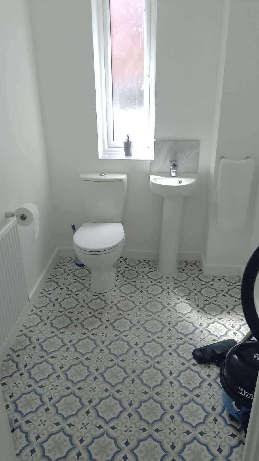 A small bathroom with a toilet, sink, and patterned floor tiles.
