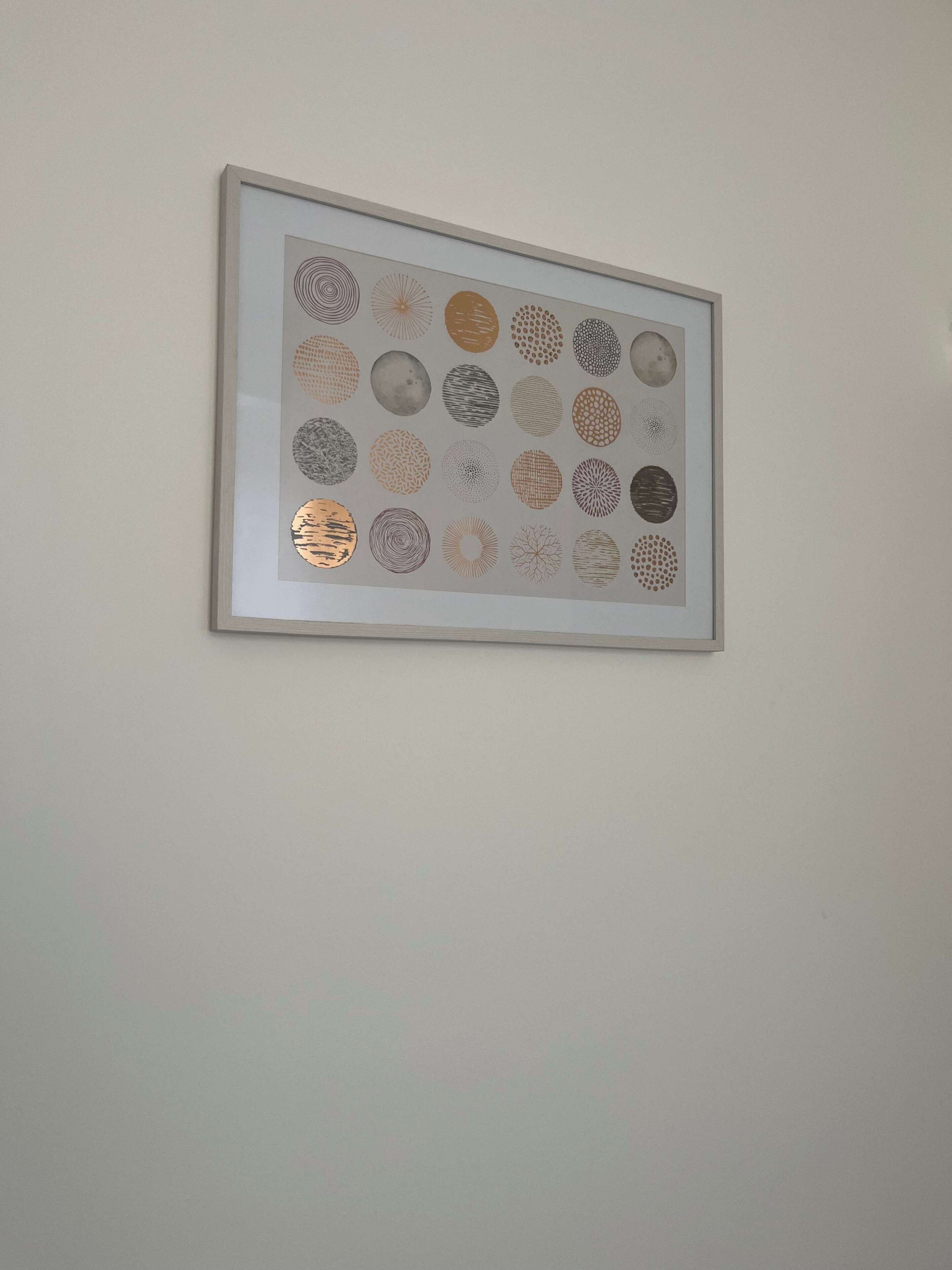 Una obra de arte enmarco con diseños circulares sobre una pared lisa.