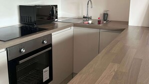 Una cucina moderna con forno a microonde, forno, lavello e cappa aspirante in acciaio inossidabile.