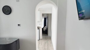 A modern living room with a dining area, a TV mounted on the wall, and a hallway leading to another room. - Ground Floor Flat with Courtyard garden (Weston-super-Mare)