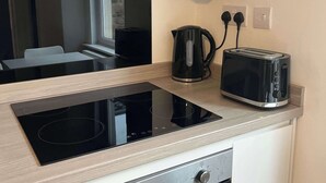 A compact kitchen with a built-in induction cooktop, a toaster, a kettle, and a dishwasher. - 1 Bed Room Flat Close to seafront (Weston-super-Mare)