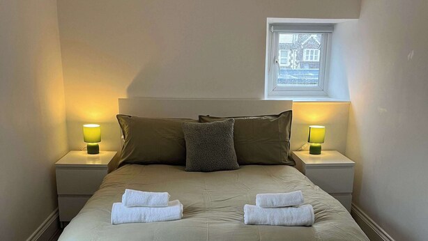A neatly made bed with two pillows, two bedside lamps, and two folded towels on the headboard. - 1 Bed Room Flat Close to seafront (Weston-super-Mare)