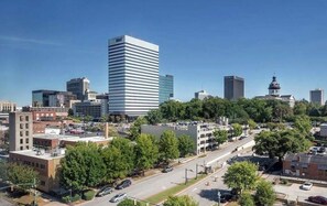 Een stadsbeeld met moderne gebouwen, een opvallend wit wolkenkrabber en een historisch pand met een toren.