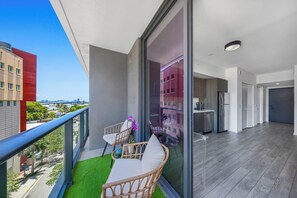 Un balcone con sedie in vimini, un tavolino e vista sulla città.