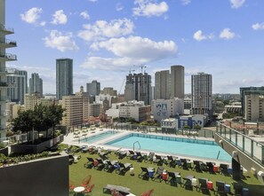 Una piscina sul tetto con poltrone relax e vista sulla città.