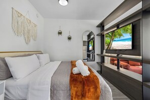 A modern hotel room with a bed, a TV, and a view of a beach. - Miami Bayside Balcony Studio Pool & Gym (Miami)