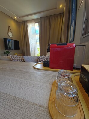 Habitación de hotel con cama, una silla roja, espacio para café, televisor y ventana con cortinas.