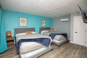 Ein Zimmer mit zwei Betten, einem Fernseher und einer Klimaanlage.