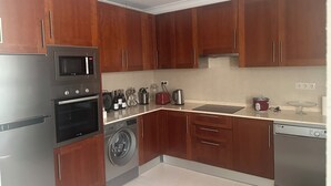 Eine moderne Küche mit Edelstahlgeräten, Holzschränken und einer integrierten Waschmaschine.