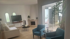 Ein Wohnzimmer mit einer Couch, zwei Sesseln, einem Fernseher, einem Kamin und einem großen Fenster mit Aussicht.