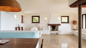 A modern living room with a fireplace, a dining area with a wooden table, and a large window with a view. - Domus Gallesi by Wonderful Italy (Portobello)