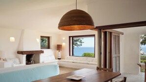A modern room with a wooden dining table, a sofa, a fireplace, and a view of the sea. - Domus Gallesi by Wonderful Italy (Portobello)