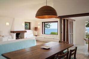 Ein modernes Zimmer mit einem Holzesstisch, einer Couch, einem Kamin und Meerblick.