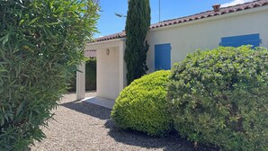 A building with a gravel driveway, a blue door, and a white wall. - House of the Palm Tree (La Brée-les-Bains)
