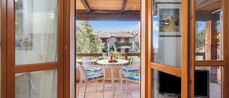 A wooden-framed glass door leading to a patio with a round table, chairs, and a television.