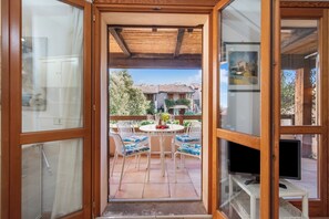 Eine Holztür mit Glasfenstern, die auf eine Terrasse mit einem runden Tisch, Stühlen und einem Fernseher führt.