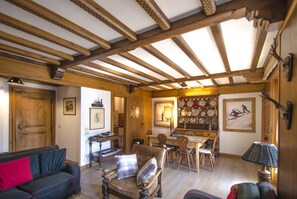Ein Zimmer mit Holzboden, einem Esstisch, Stühlen, einer Couch und einer Lampe.