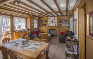 Ein Holzinnenraum mit einem Esstisch, Stühlen, einem Kamin, Bücherregalen und einem aufgehängten Damhirschschädel.