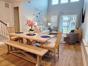 Ein Essbereich mit Holztisch und Bänken, ein Wohnzimmer mit Sofa und Couchtisch sowie eine Treppe.