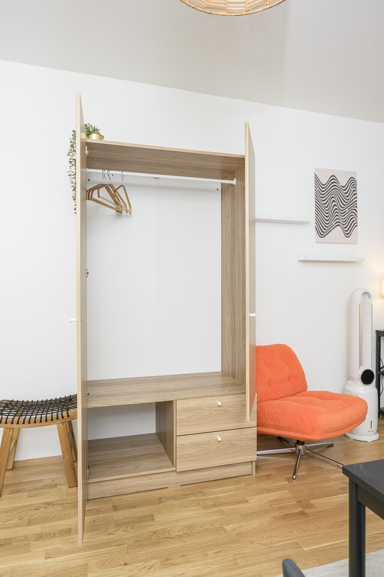 A room with a wooden wardrobe, a bench, an orange chair, and a wall-mounted air purifier.