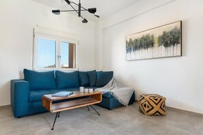 A modern living room with a blue sofa, a wooden coffee table, and a painting on the wall. - Ocean Alley Seaside Retreats (K. Gouves)