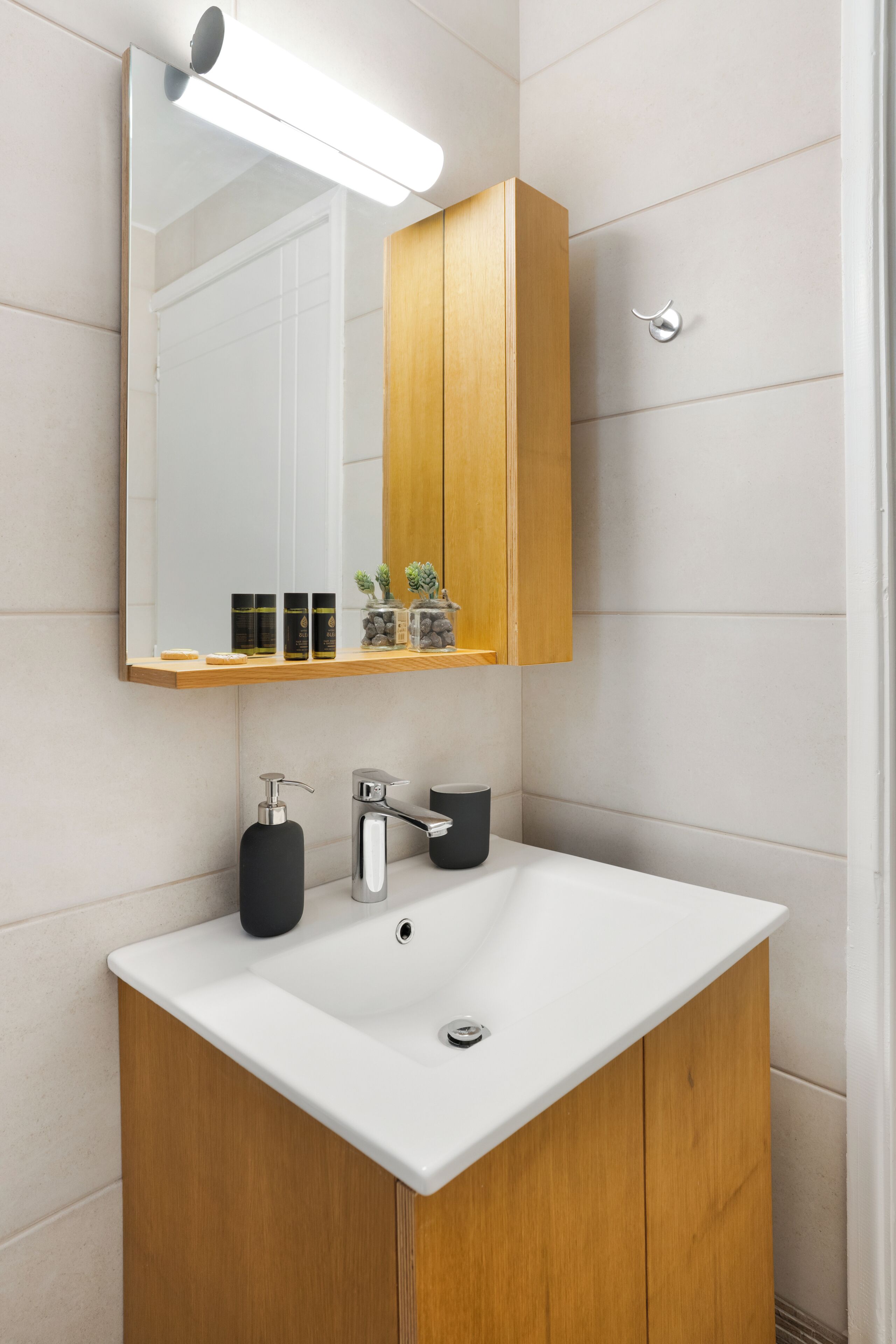 Ein Badezimmer mit einem weißen Waschbecken, einem Holzschranken und Regalen für Pflegeprodukte.
