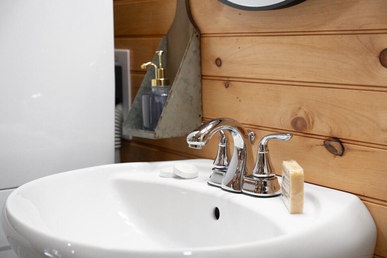 A white bathroom sink with a chrome faucet, a soap bar, and a bottle of hand soap.