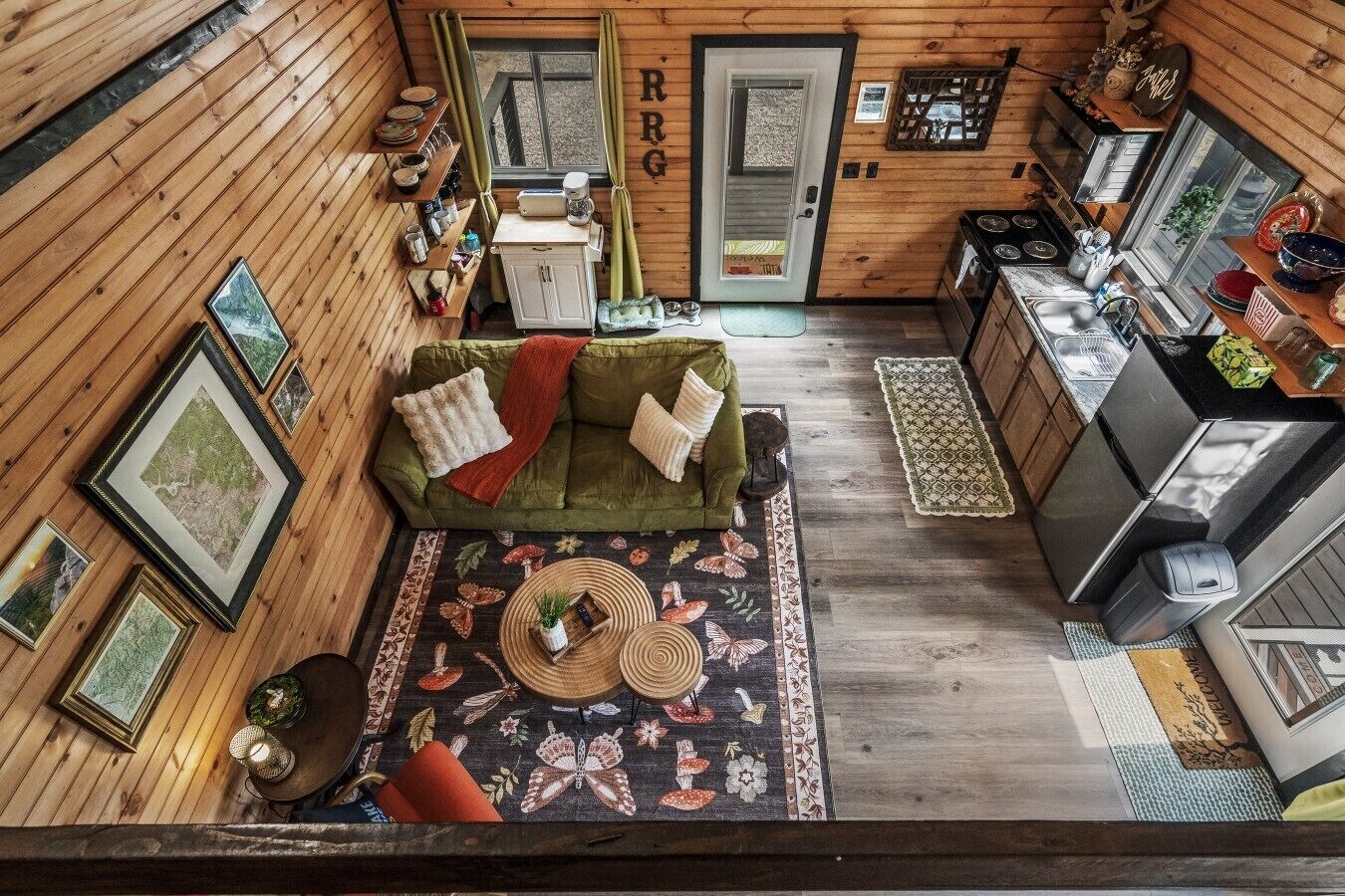 A cozy cabin interior with a green sofa, a kitchen area, and a dining table.