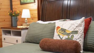 Un letto con una coperta verde, un cuscino marrone e un cuscino decorativo con un motivo a uccello.